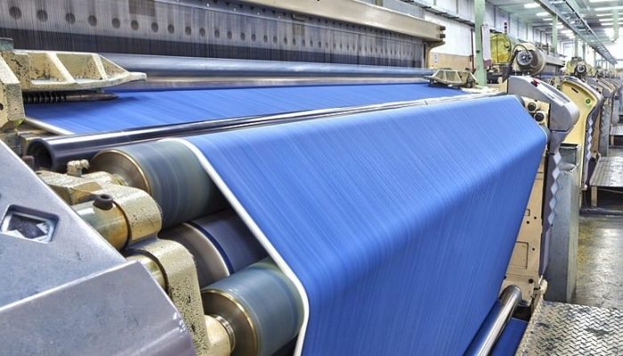 Weaving fabric on air jet looms in big textile weaving unit.